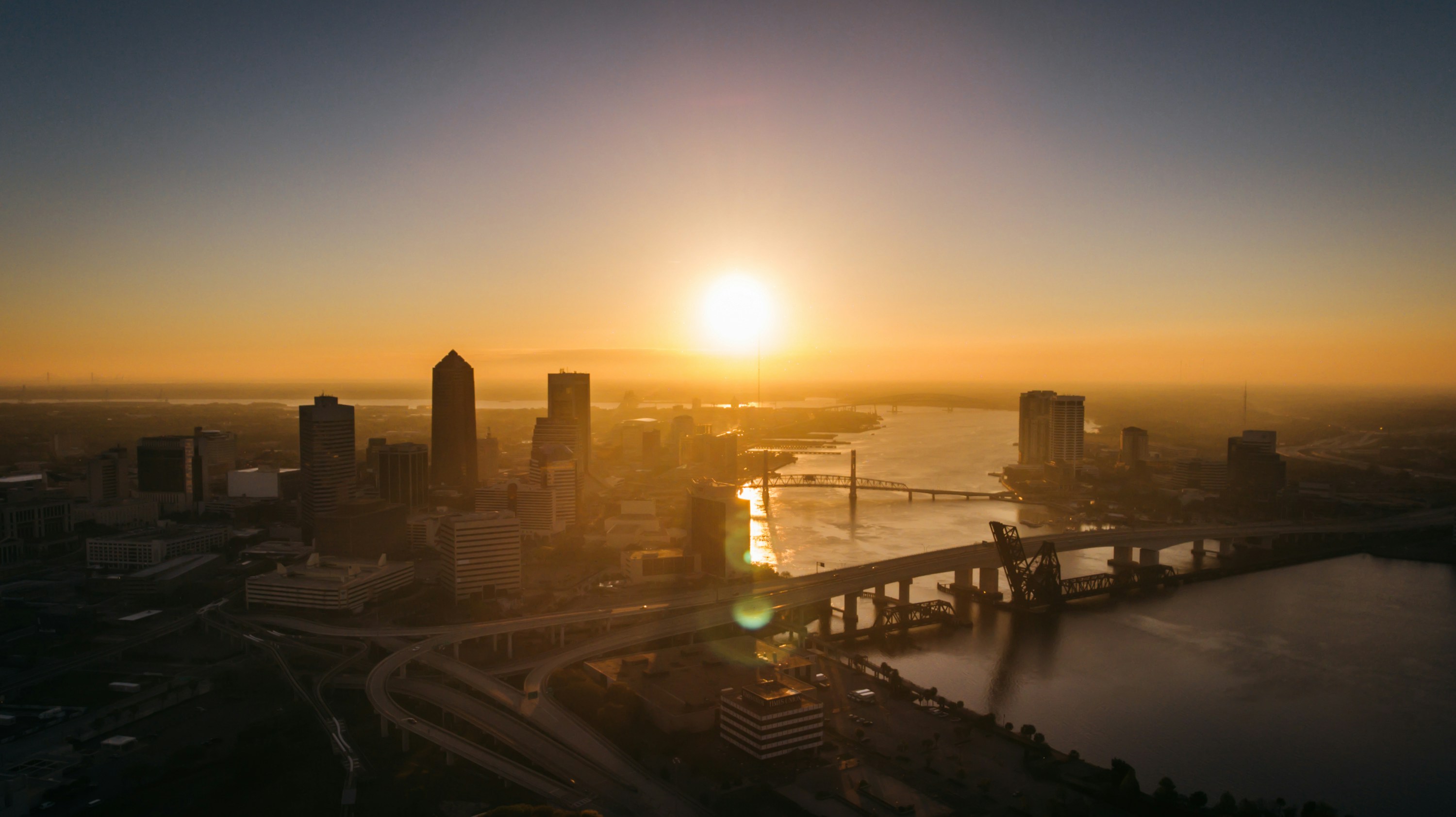 Aerial view of a city, river bridges and transport infrastructure at sunset